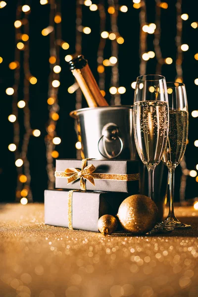 Superficie nivel de regalos, copas de champán y bolas sobre fondo claro guirnalda, concepto de Navidad - foto de stock