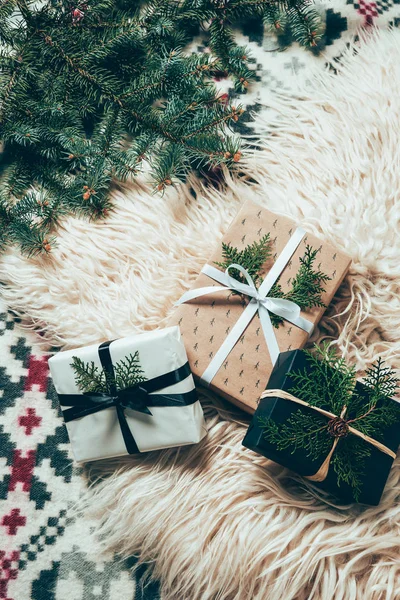 Flat lay with pine tree branches and wrapped christmas presents on woolen backdrop — Stock Photo