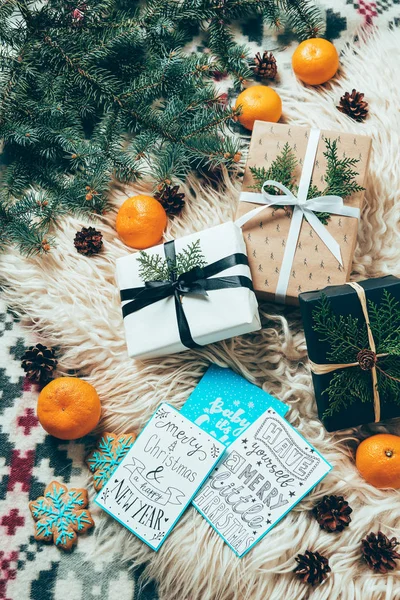 Flat lay with pine tree branches, winter postcards and wrapped christmas presents on woolen backdrop — Stock Photo