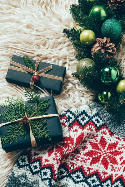 Vue du dessus des cadeaux de Noël enveloppés, de la couronne de Noël et du pull d'hiver sur fond de laine — Photo de stock