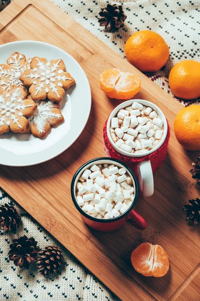 Vista superior de las tazas de chocolate caliente con malvaviscos, galletas y mandarinas sobre fondo manta, concepto de desayuno de Navidad — Stock Photo