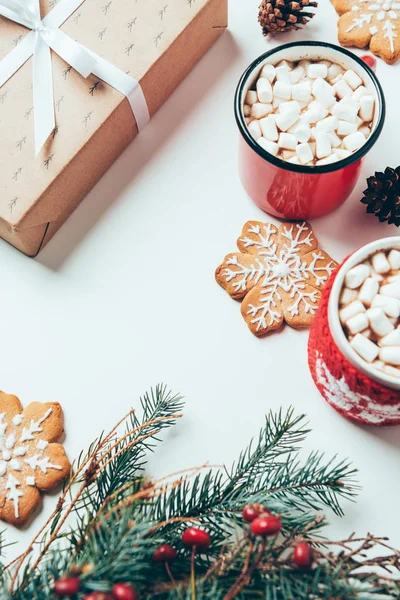 Vista dall'alto di tazze di cioccolata calda con marshmallow, biscotti e Natale presenti sul tavolo bianco, concetto di colazione natalizia — Foto stock