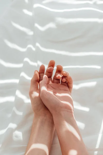 Cropped shot of loving couple lying on white bed sheet together — Stock Photo