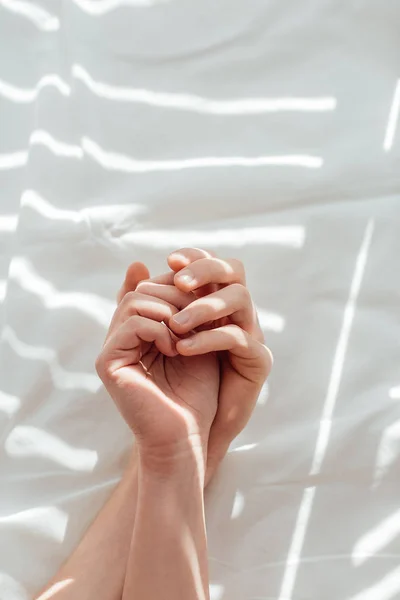 Cropped shot of loving couple lying on white bed sheet together — Stock Photo