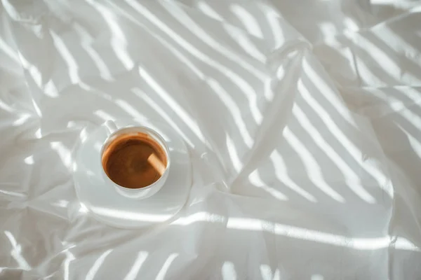 Vue du dessus de tasse de café aromatique sur drap de lit blanc — Photo de stock