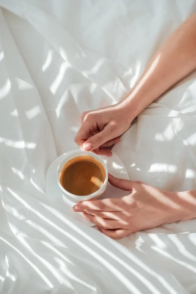 Partial view of woman with cup of coffee in bed in morning — Stock Photo