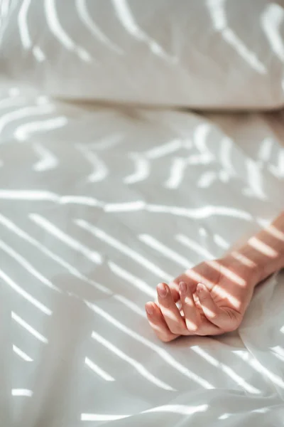 Cropped shot of female hand on white bed sheet — Stock Photo