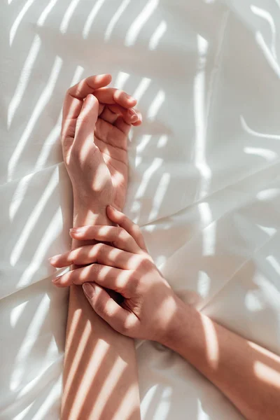 Cropped shot of female hands on white bed sheet — Stock Photo