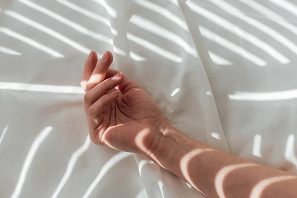 Plan recadré de la main féminine sur drap de lit blanc — Photo de stock
