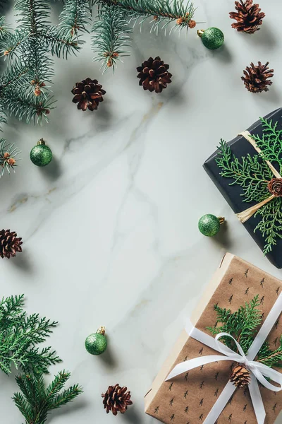Вид зверху різдвяні подарункові коробки з ялинковими гілками та сосновими шишками на мармуровому фоні з місцем для тексту — стокове фото