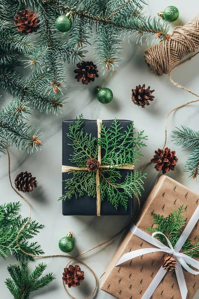 Vista superior de cajas de regalo con bolas de Navidad y conos de pino en la mesa de mármol - foto de stock