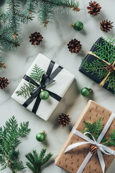 Flache Liege mit Geschenken, Weihnachtskugeln und Tannenzapfen auf Marmortisch — Stockfoto