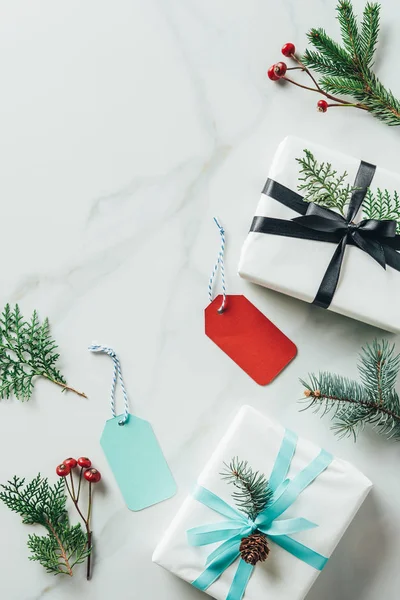 Top view of christmas gifts with fir branches and tags on marble table with copy space — Stock Photo