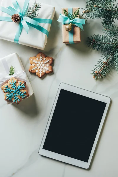 Верхний вид рождественских подарков, снежинки печенье и цифровой планшет с чистым экраном на мраморном фоне — стоковое фото
