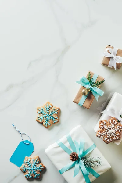 Vista superior de presentes de Natal e biscoitos floco de neve com gelo no fundo de mármore com espaço de cópia — Fotografia de Stock