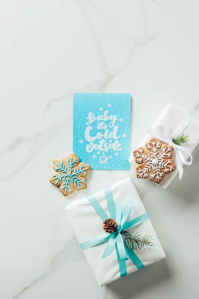 Вид на белый рождественский подарок, печенье со снежинками и поздравительная открытка с надписью 