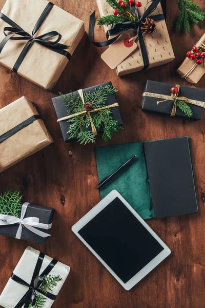 Cama plana con cajas de regalo de Navidad, diario y tableta digital con pantalla en blanco sobre fondo de madera - foto de stock
