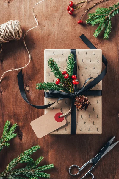 Vista dall'alto del Natale presente con rami di abete, bacche decorative e tag su sfondo di legno — Foto stock