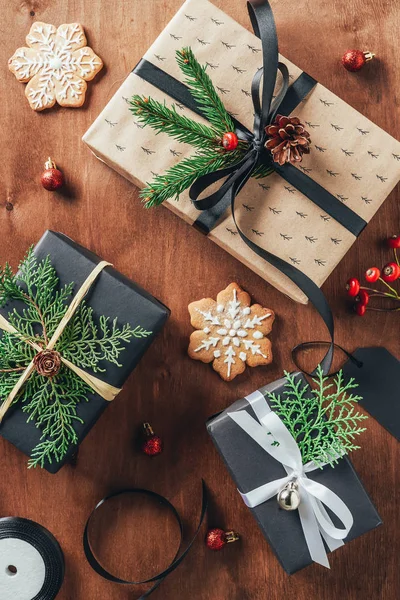 Posa piatta con regali, palle di Natale, rami di abete e biscotti su sfondo di legno — Foto stock