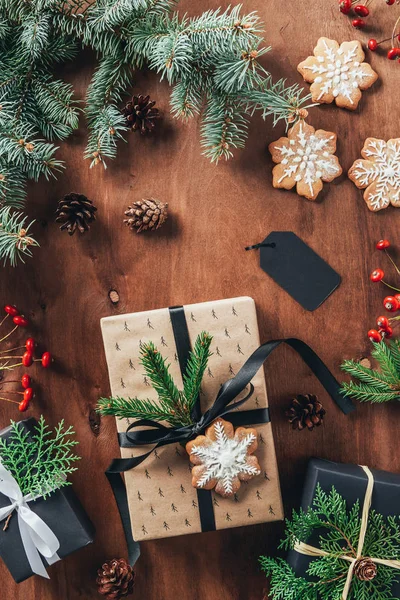 Piso con regalos de Navidad, ramas de abeto y galletas sobre fondo de madera - foto de stock