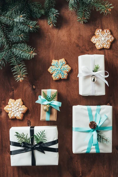 Flache Lage mit Weihnachtsgeschenkschachteln mit Tannenzweigen und Plätzchen auf Holzgrund — Stockfoto