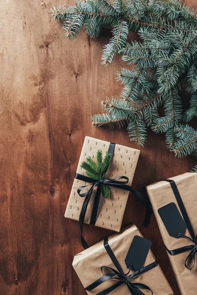 Plano con regalos de Navidad, ramas de abeto y etiquetas sobre fondo de madera con espacio de copia - foto de stock