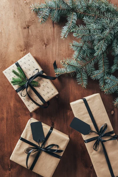 Top view of christmas gifts with fir branches and tags on wooden background — Stock Photo