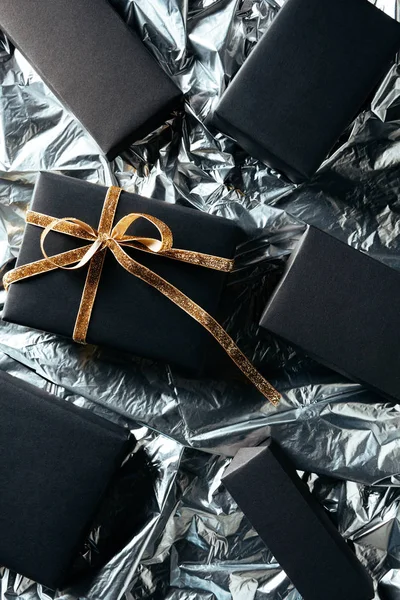 Flat lay com presente arranjado com fita dourada e caixas pretas em branco no fundo de papel de embrulho de prata — Fotografia de Stock