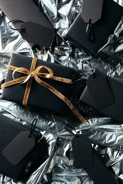 Flache Lage mit arrangiertem Geschenk, Schachteln und unbeschriebenen Preisschildern auf silbernem Geschenkpapier-Hintergrund, Black-Friday-Konzept — Stockfoto