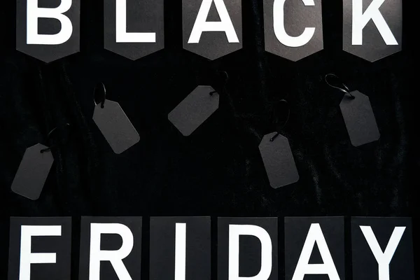 Top view of black friday lettering and blank price tags on black background — Stock Photo