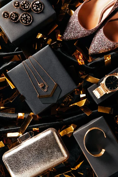 Flat lay with feminine shoes, purse and jewelry on black background with golden confetti — Stock Photo