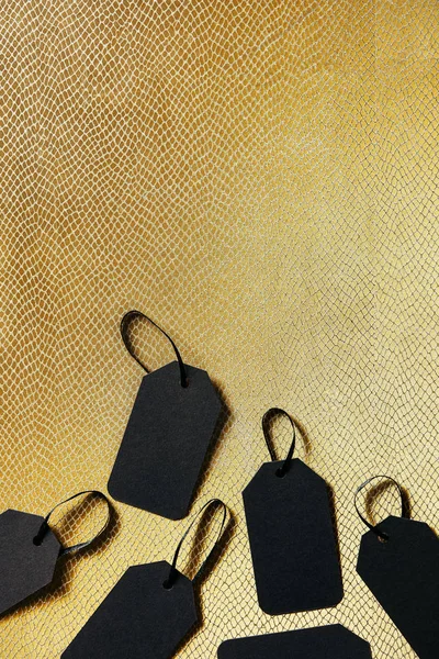 Vue du haut des étiquettes de prix vierges noires sur fond doré, concept du vendredi noir — Photo de stock
