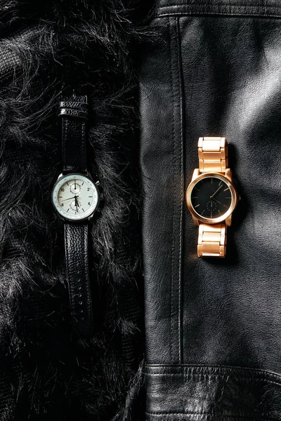Draufsicht auf luxuriöse maskuline und feminine Armbanduhren auf schwarzem Leder und wollenem Hintergrund — Stockfoto