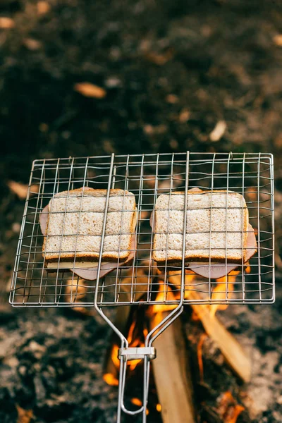 Two sandwiches roasting on grill grate over fire — Stock Photo