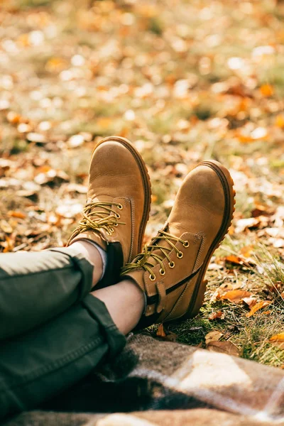 Abgeschnittene Paar orangefarbene Stiefel auf Hintergrund aus buntem Laub — Stockfoto