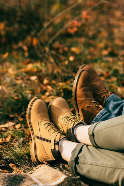 Cropped view on two pairs of orange boots in beautiful foliage in autumn — Stock Photo