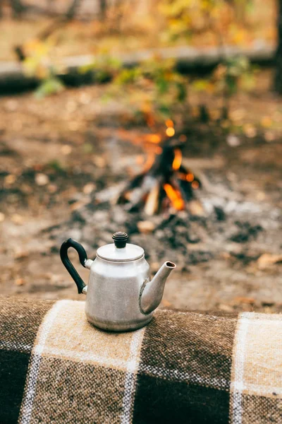 Metallischer Wasserkocher auf verschwommenem Herbsthintergrund mit Lagerfeuer — Stockfoto