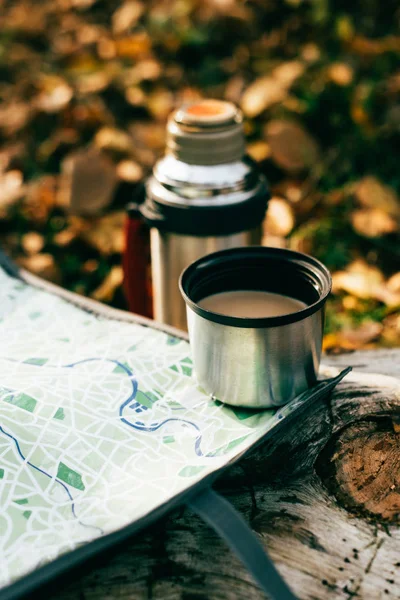 Café en la taza de termo metálico en el mapa de viaje sobre fondo otoñal borrosa - foto de stock