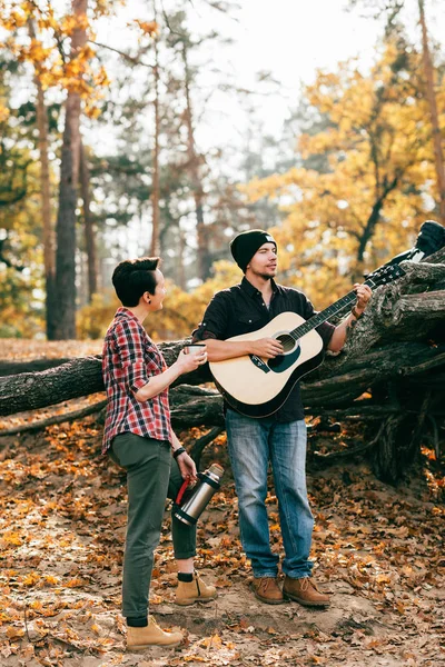 Adult woman and man having fun with guitar on autumal background — Stock Photo