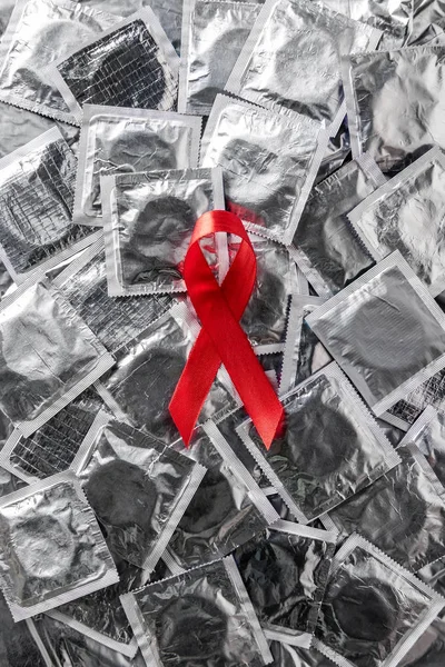 Top view of aids awareness red ribbon on silver condoms — Stock Photo