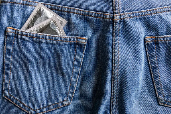 Pair of silver condoms in pocket of blue jeans — Stock Photo