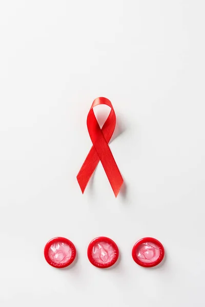 Vista superior de SIDA conciencia cinta roja y condones rojos sobre fondo blanco - foto de stock