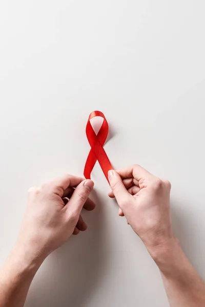 Male hands holding aids awareness red ribbon on white background — Stock Photo