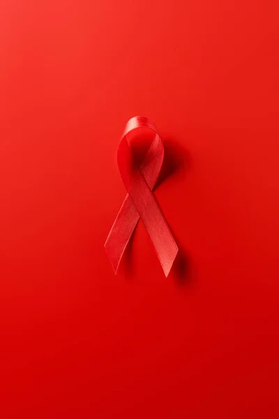Top view of aids awareness red ribbon on red background — Stock Photo