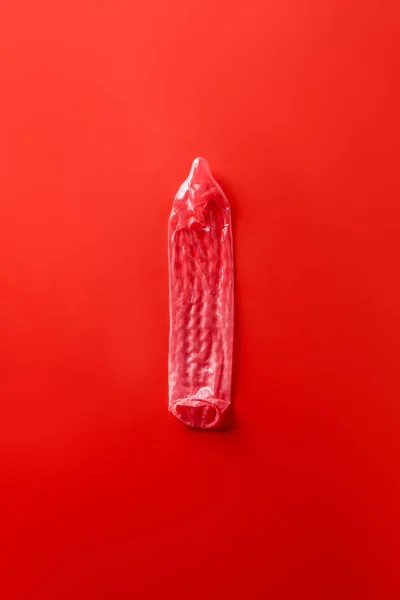 Vista superior del condón rojo sobre fondo rojo - foto de stock