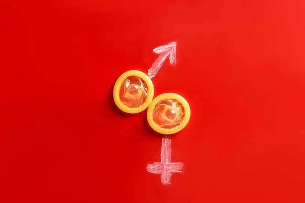 Top view of condoms with male and female signs on red background — Stock Photo