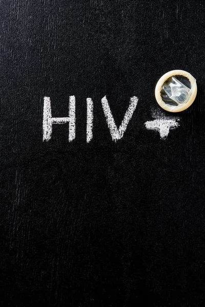 Vista superior del condón con signo de hiv sobre fondo negro - foto de stock