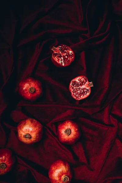 Top view of arranged pomegranates on red velvet fabric background — Stock Photo