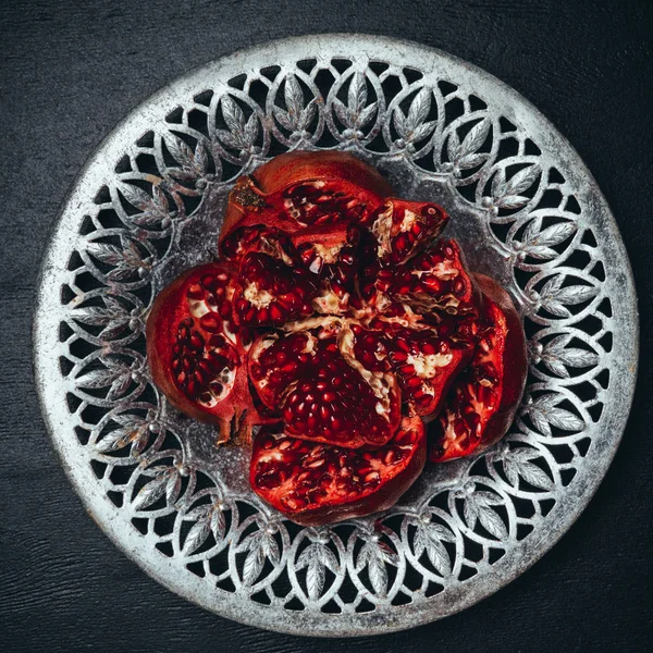 Top view of cut fresh garnets in metal bowl on black tabletop — Stock Photo