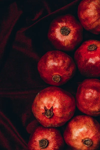 Top view of arranged pomegranates on red velvet fabric background — Stock Photo